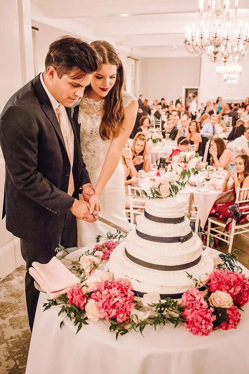 A newly married couple at the wedding reception cutting the cake.